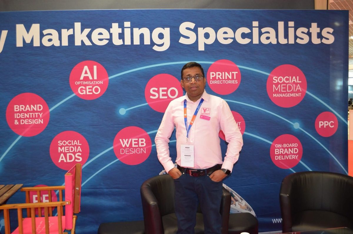 Sanjeev Gabriel at the Yachting Pages stand in front of a digital marketing services backdrop