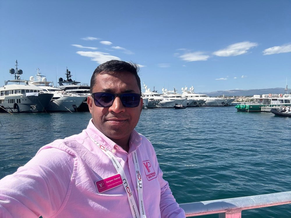 Sanjeev Gabriel taking a selfie by a marina full of superyachts