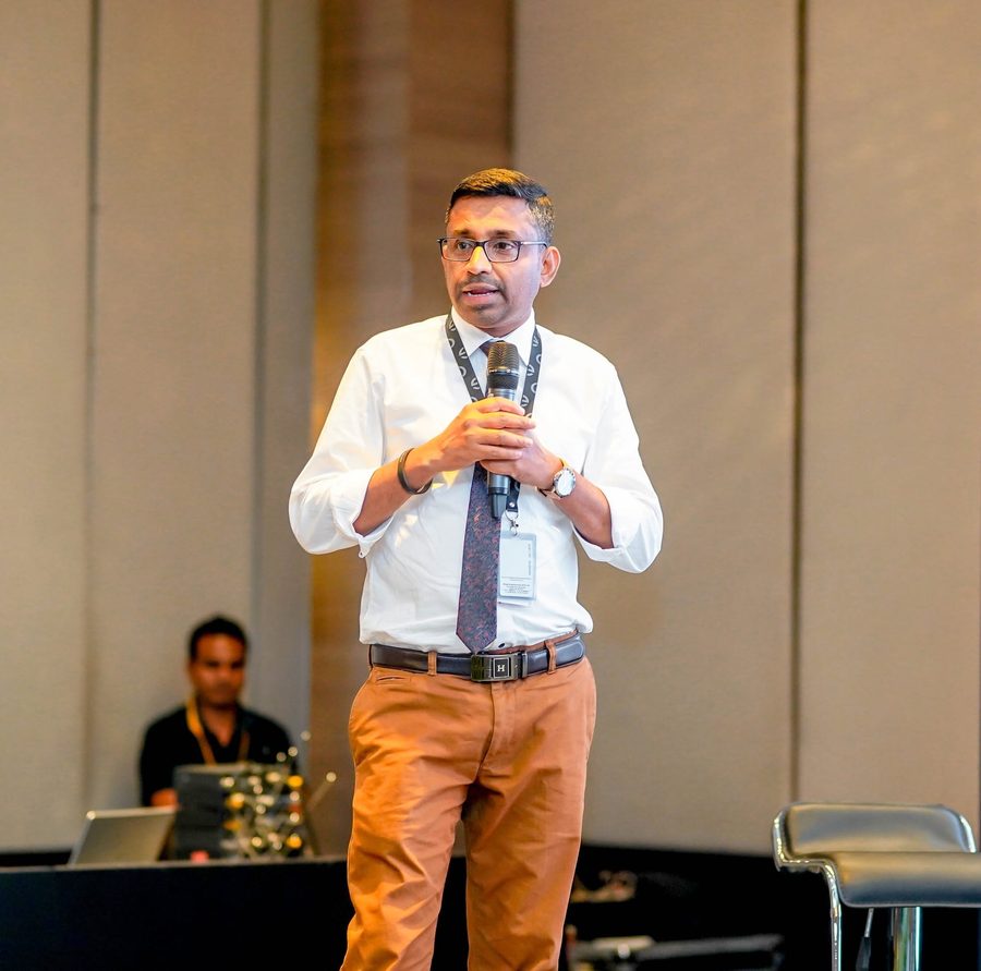 Sanjeev Gabriel speaking with a microphone at a conference